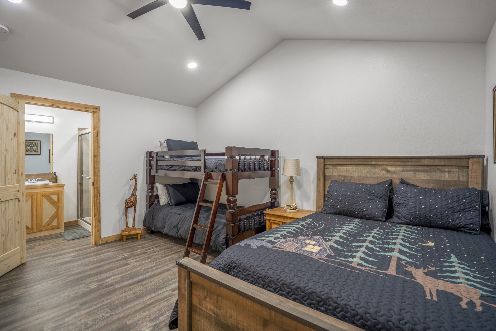 Inspira Ranch barndominium bedroom with bunk bed and queen bed under a vaulted ceiling