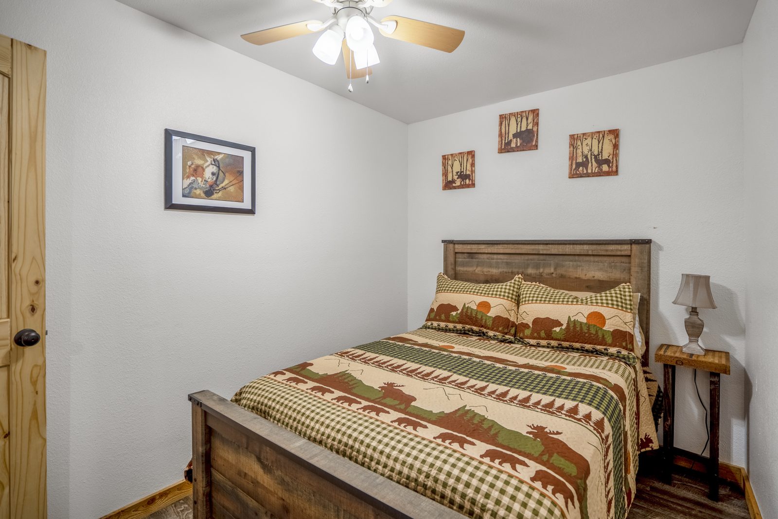 Inspira Ranch barndominium queen bedroom with cabin-style bedding and framed art