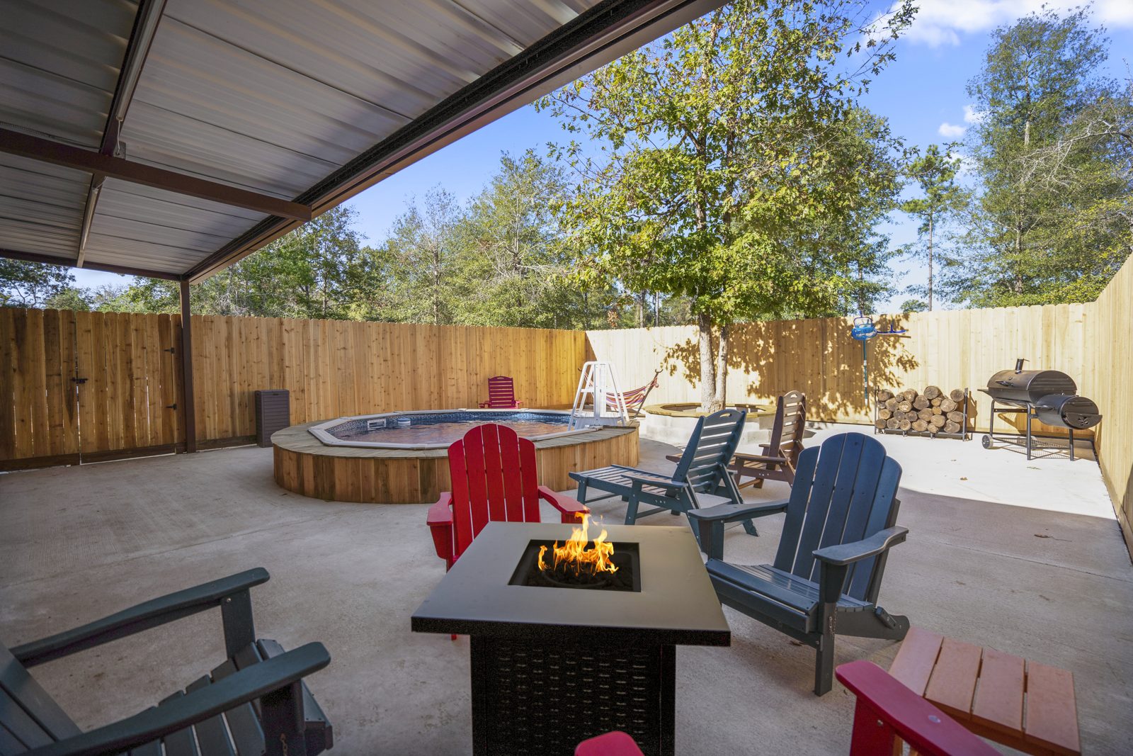 Inspira Ranch barndominium covered patio with hot tub, fire pit table, and Adirondack chairs