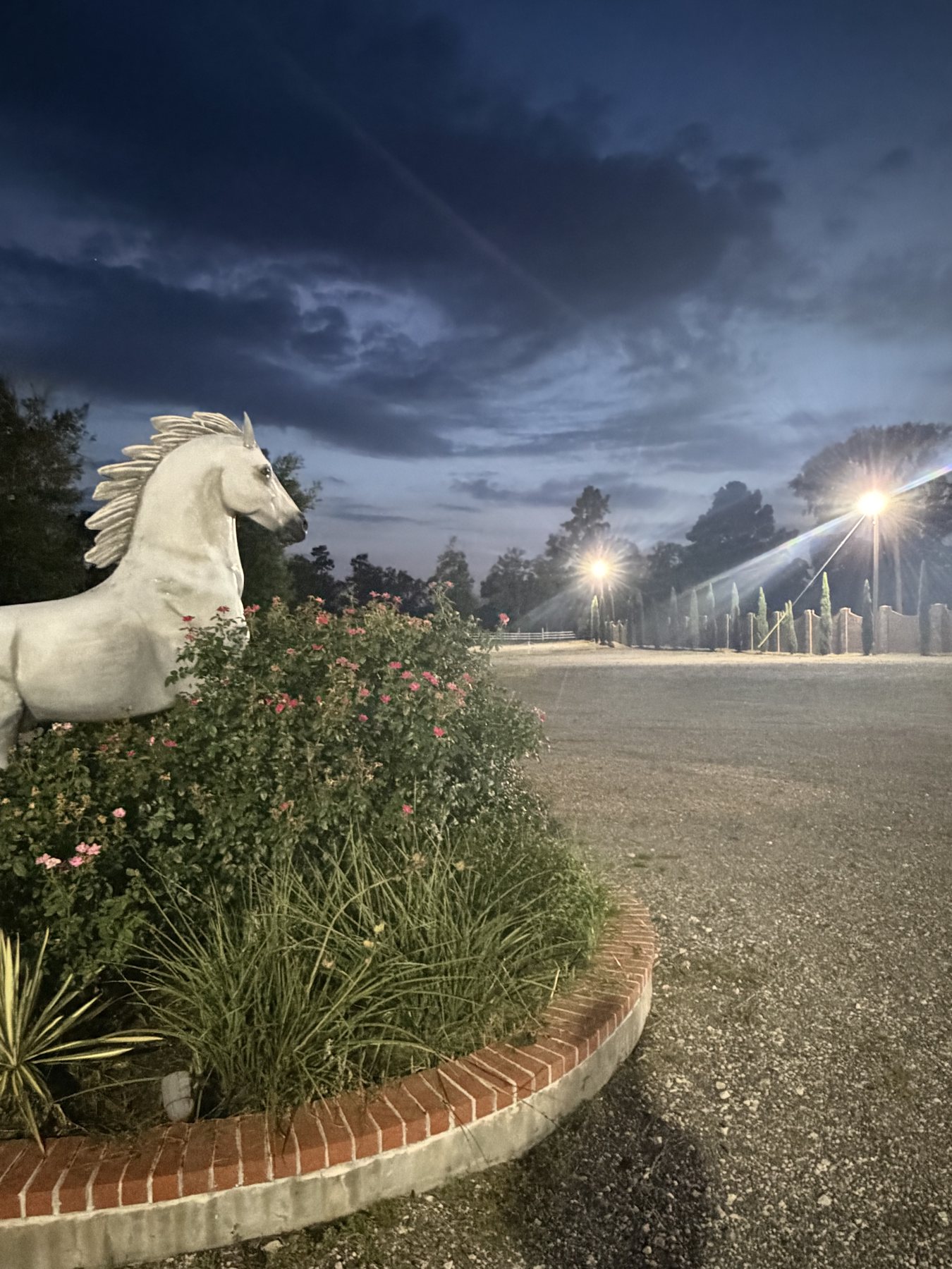 Inspira Ranch's illuminated white rearing horse statue, the property's icon, at dusk under a pink Texas sky
