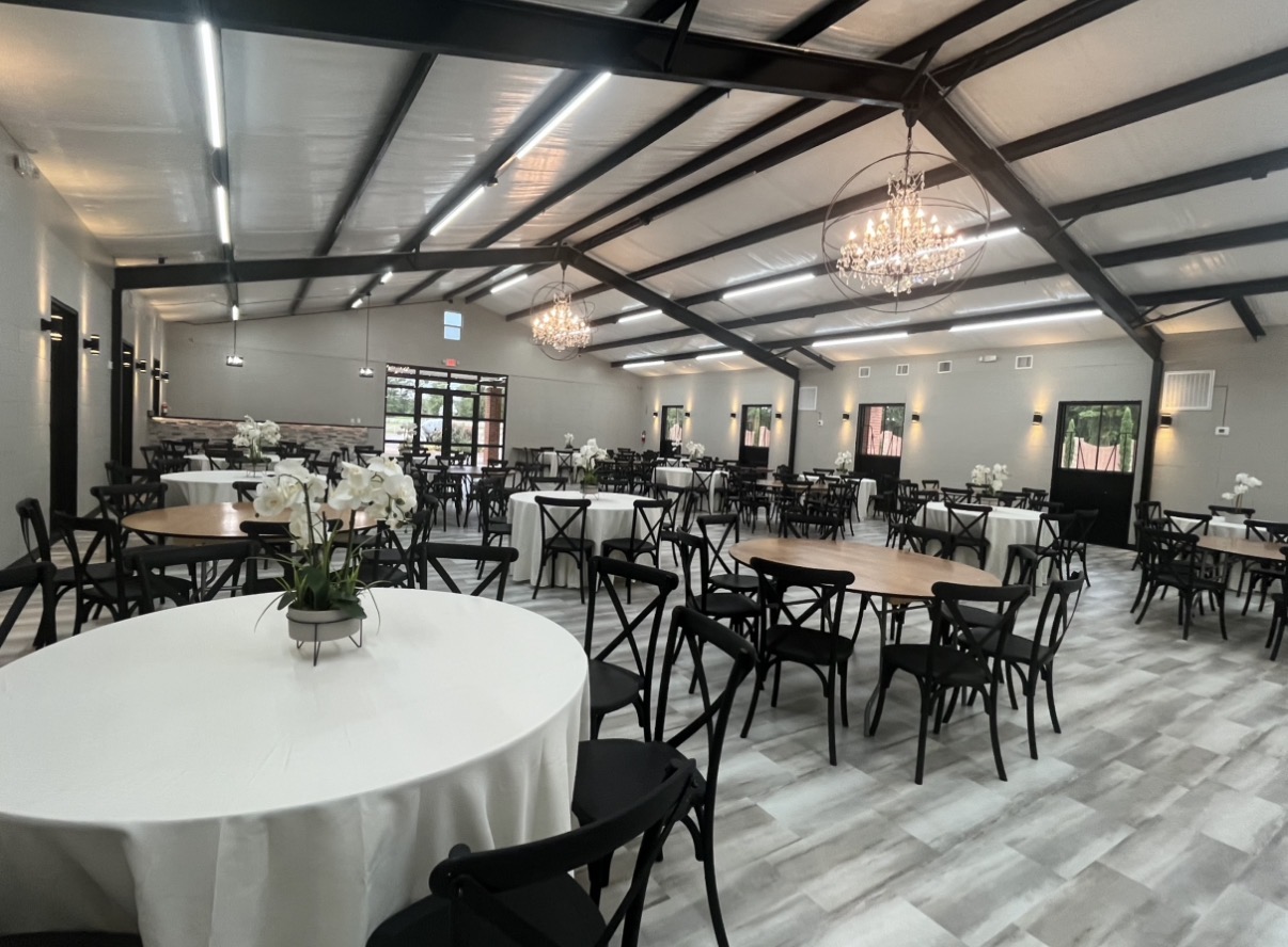 Inspira Ranch event hall set with round tables, orchid centerpieces, and orbit chandeliers