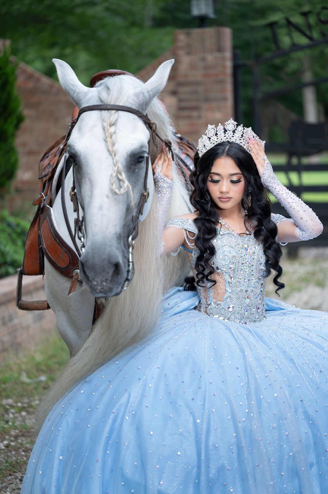 Close-up portrait of a quinceañera with tiara next to a white horse