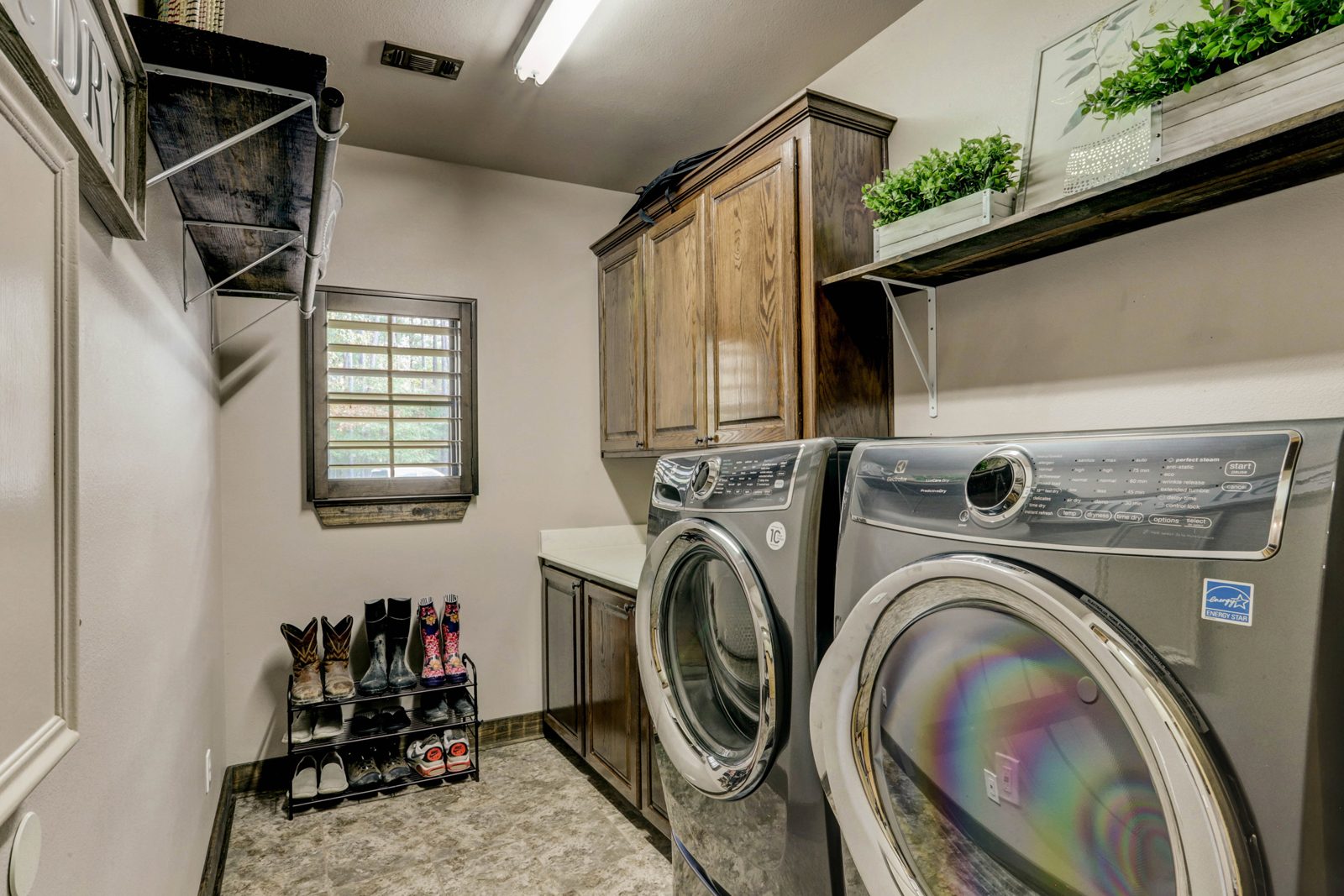 Inspira Ranch main house laundry room with full-size washer and dryer and wood cabinetry